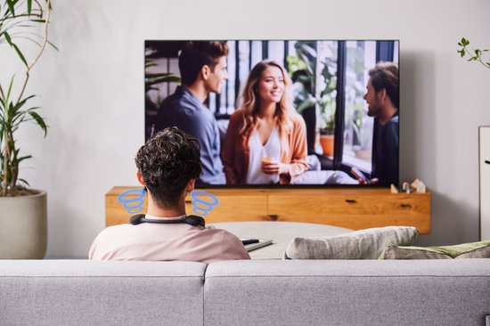 Man van achteren gezien, draagt een nekband speaker en kijkt tv. Blauwe geluidsgolven om zijn hoofd.