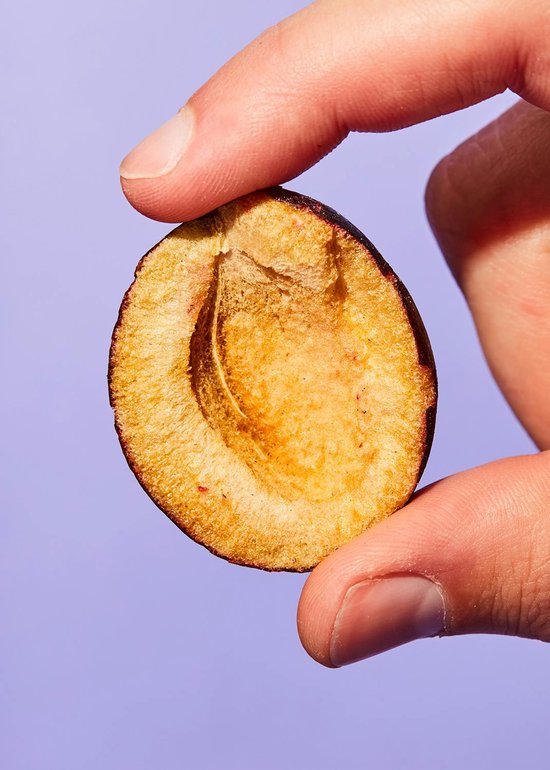 Een gehalveerde pruim in een hand.