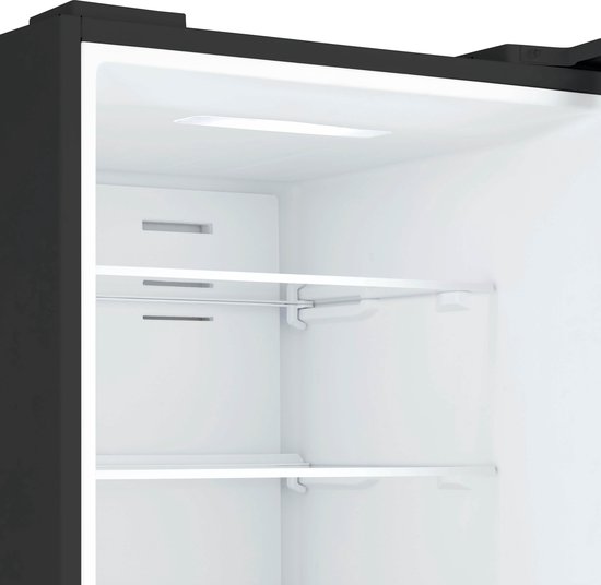Leeg interieur van een zwarte Inventum koel-vriescombinatie met twee glazen planken.