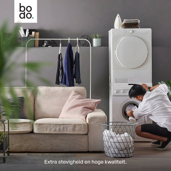 Woonkamer met een beige bank, wasmachine en droger gestapeld. Een man doet de was. Tekst: 'Extra stevigheid en hoge kwaliteit.'