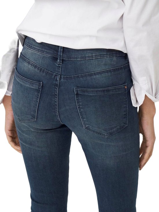 Achterkant van een donkerblauwe skinny jeans met middelhoge taille, lichte wassing en gedetailleerde achterzakken.