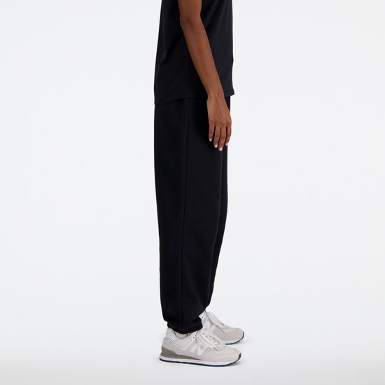 Zijaanzicht van een zwarte New Balance joggingbroek met wit logo.
