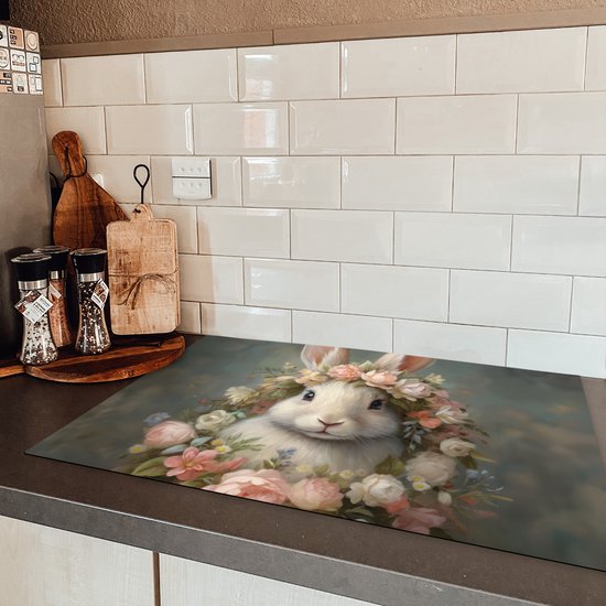 Een inductiebeschermer met een konijn versierd met bloemen, geplaatst op een donker aanrecht.