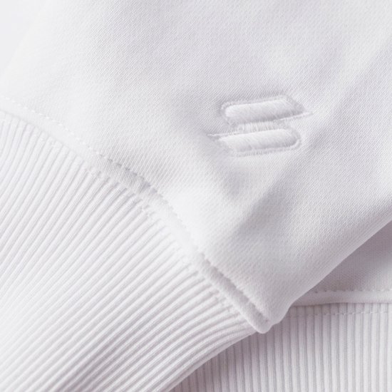 Détail de l'ourlet d'un sweat blanc avec logo brodé.
