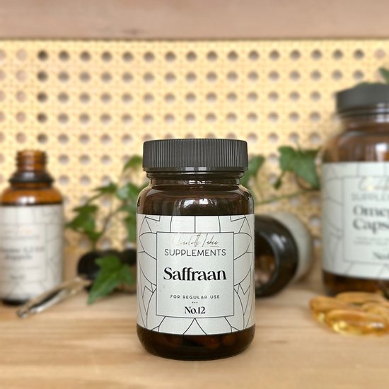 Bruine supplementenfles met etiket "Saffraan SUPPLEMENTS FOR REGULAR USE No.12" op een plank met andere potjes en planten.