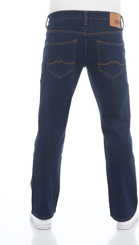 Man in donkerblauwe bootcut jeans met oranje stiksels en witte sneakers, van achteren gezien.