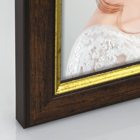 Detail van een houten fotolijst met gouden rand, een stukje van een bruid met een kanten jurk.