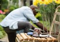 Smartphone met babyfoonweergave op picknicktafel, man tuiniert op achtergrond.