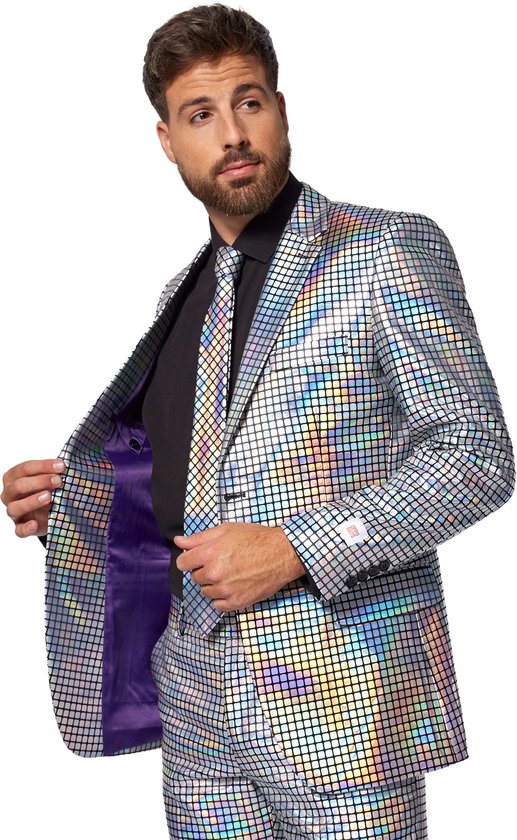 Man in zilveren disco glitter pak met ruitenpatroon, opent de revers met de linkerhand, zichtbare paarse voering.
