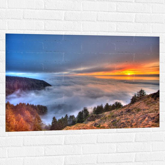 WallClassics - Muursticker - Zonsondergang boven de Wolken bij Berg - 105x70 cm Foto op Muursticker