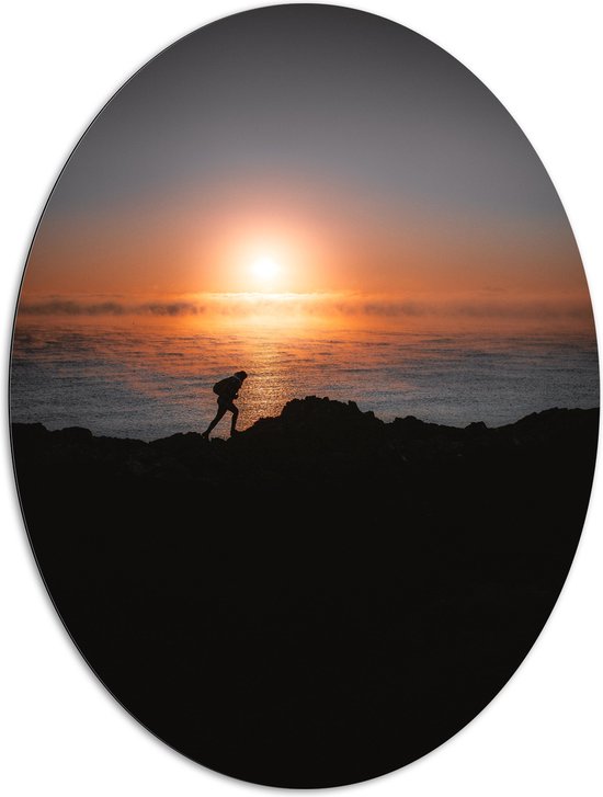 WallClassics - Dibond Ovaal - Man lopend over Berg aan de Zee met Zonsondergang - 81x108 cm Foto op Ovaal (Met Ophangsysteem)