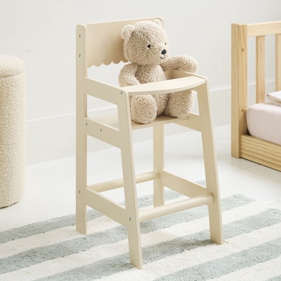 Crèmekleurige poppenstoel met geschulpte rugleuning, met een knuffelbeer die erop zit.