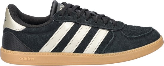 Zwarte Adidas sneaker met beige zool, witte strepen en gouden accenten op de hiel.