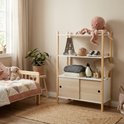 Boekenkast met houten frame, witte planken en lichte houten deuren, in kinderkamer met decoratie.