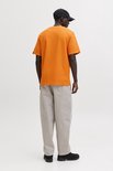 Een man draagt een oranje wafel t-shirt, beige broek en zwarte pet, van achteren gezien.