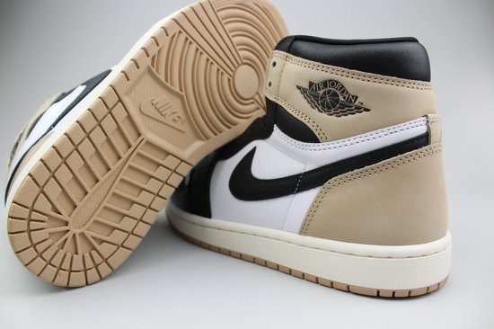 Gedetailleerde close-up van een Jordan 1 Retro High OG 'Latte' sneaker in beige, zwart en wit, met zool.