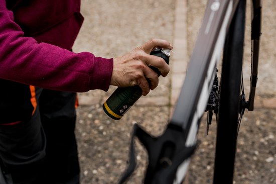 Hand spuit met de remreiniger op een fietswiel.