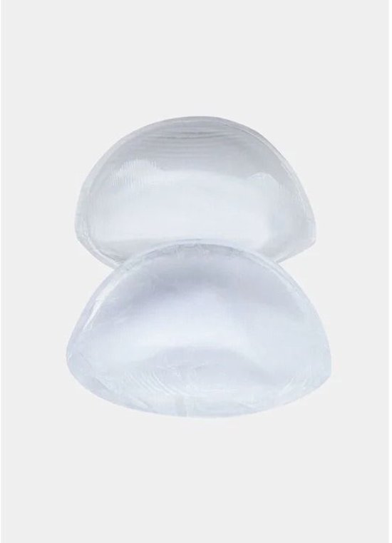 Twee doorzichtige, gel-gevulde siliconen push-up pads in halvemaanvorm, op een grijze achtergrond.