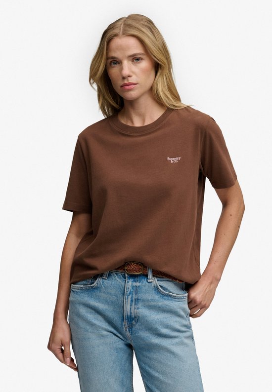 Bruin Superdry T-shirt met geborduurde tekst op de borst, gedragen door een model.