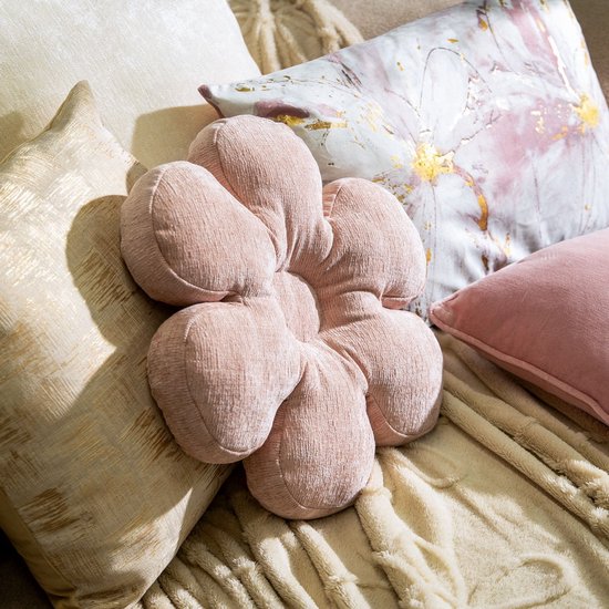 Roze bloemvormig kussen met reliëf in de textuur, omringd door andere sierkussens.