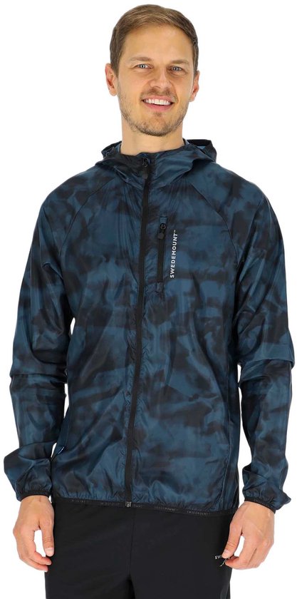 Homme, vu de face, souriant et portant une veste coupe-vent à capuche camouflage bleu foncé avec le logo 'SWEDEMOUNT'.