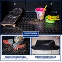 Zwarte kofferbakmat met nopjespatroon, naast een skateboard en emmer, en met voetbalschoenen.