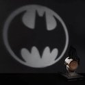 Schaduw van het vleermuislogo van Batman geprojecteerd op een muur, met de lamp ernaast.
