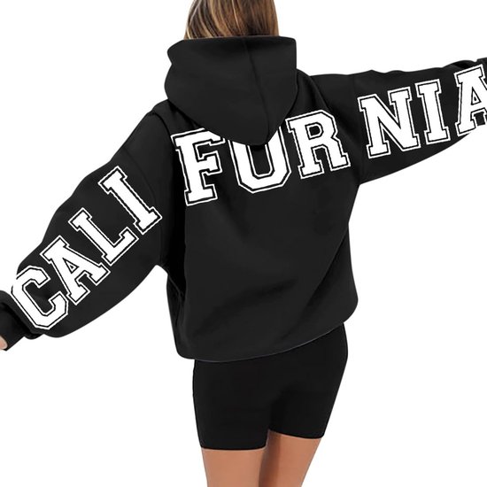 Vrouw in zwarte hoodie met 'CALI FOR NIA' op de mouwen en rug.