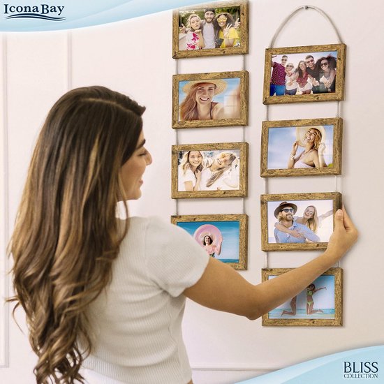 Vrouw hangt fotolijst aan een collage van acht houten fotolijsten met touw ophanging.