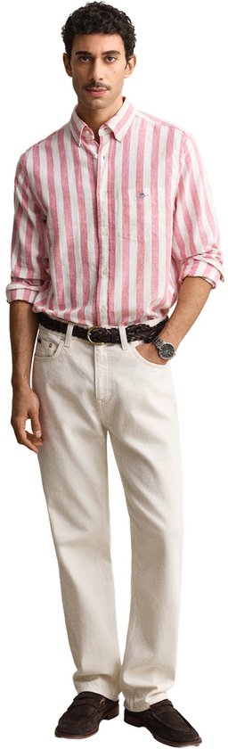 Man met een roze en witte gestreepte linnen mix blouse, beige jeans, donkere riem en schoenen.