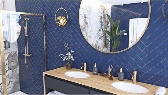 Salle de bain avec lavabo double, robinets dorés et miroir rond. Les murs sont recouverts de carreaux bleu marine en chevrons.
