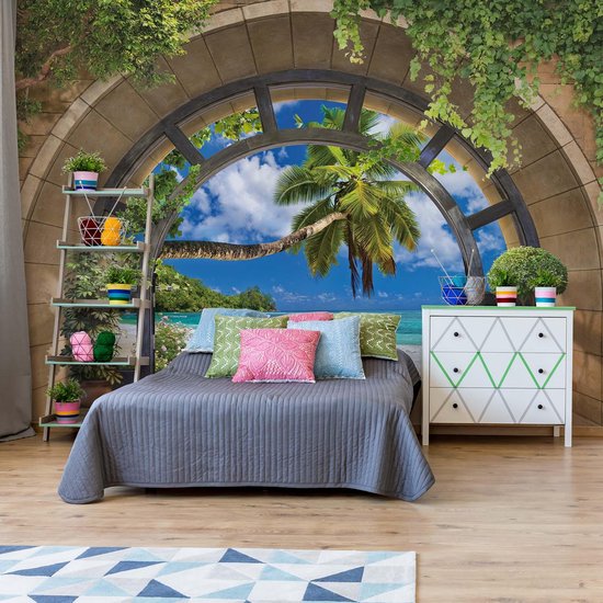 Papier peint d'une chambre avec un lit, donnant sur la scène de plage tropicale par une arche en pierre.