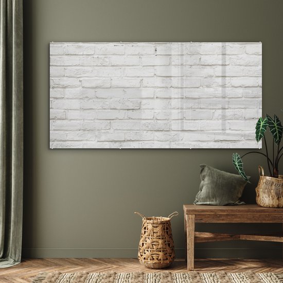 Acrylglas schilderij met witte baksteen textuur, hangend boven een houten meubel in een woonkamer met groene gordijnen.