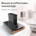 Een zwarte capsulehouder met bamboe lade vol met kleurrijke koffiecups, met een koffiezetapparaat erop.