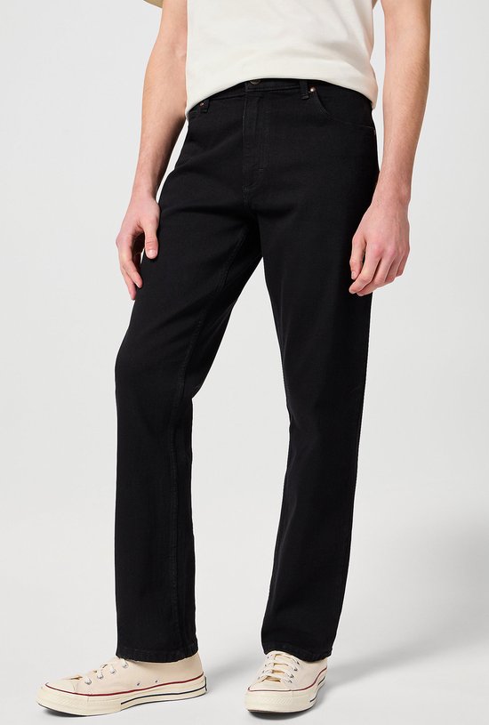 Zij-aanzicht van een man in een zwarte jeans en wit T-shirt.