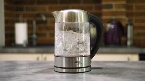 Glazen waterkoker met RVS basis, met kokend water en rode verlichting.
