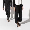 Model draagt zwarte Birkenstock Arizona slippers met jeans, een man en vrouw lopen.