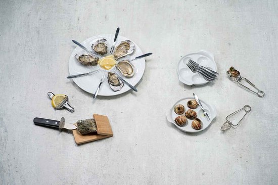 Een tafel met zeevruchten: oesters, slakken, citroenpartje, slakkentang, oestermes en citroenpers.