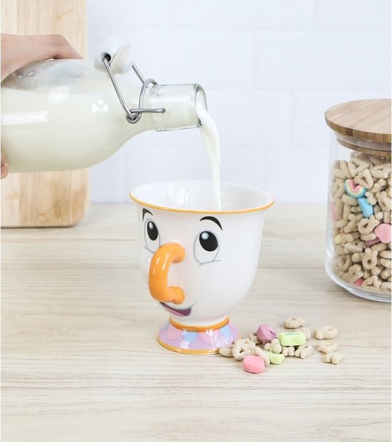 Du lait est versé dans un mug blanc avec le visage de Chip, nez orange et base colorée.