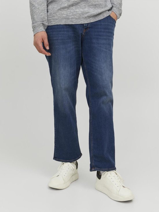 Man met blauwe jeans, grijze trui en witte sneakers.