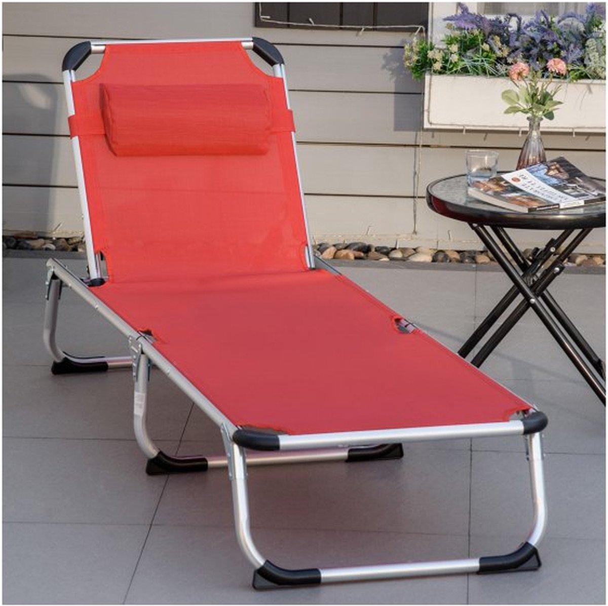 Opvouwbare relaxligstoel van aluminium met stoffen zitting in tuinsetting.