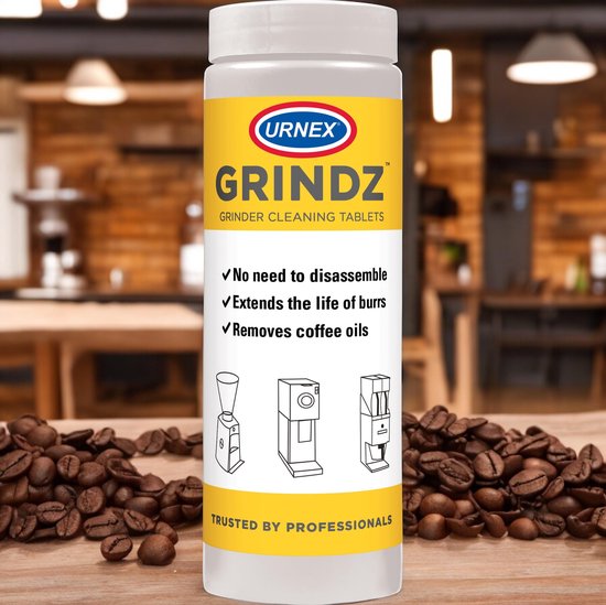 Een pot Urnex Grindz wordt leeggeschonken in de hopper van een koffiemolen.