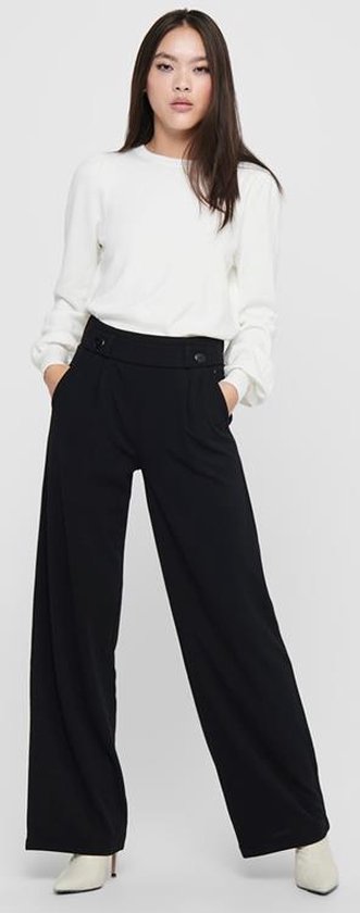 Model met zwarte wijde pantalon met hoge taille, twee knopen en steekzakken.