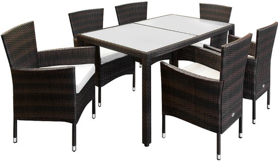 Bruine polyrattan tuintafel met glazen blad, geflankeerd door 6 bruine polyrattan stoelen met witte kussens.