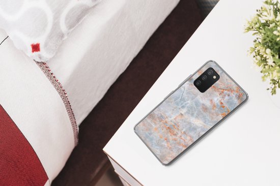 Telefoonhoesje met marmerprint in grijs, wit en oranje, liggend op een nachtkastje naast een bed.