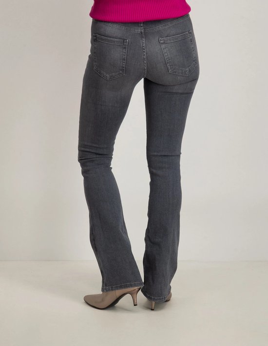 Model van achteren in grijze flared jeans en metallic enkellaarsjes.