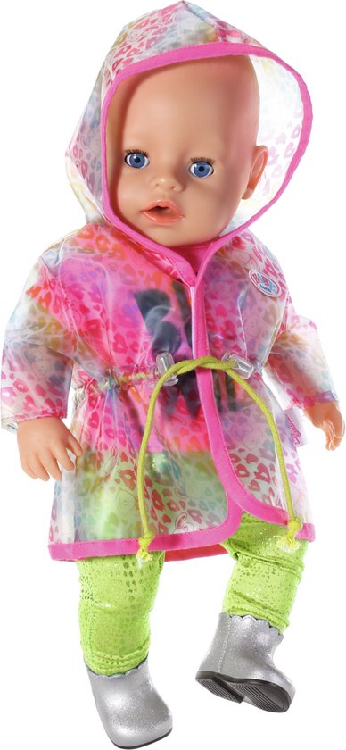 Baby pop draagt roze 'BE WILD' shirt, groene broek, zilveren laarsjes en een doorzichtige regenjas met regenboogprint.