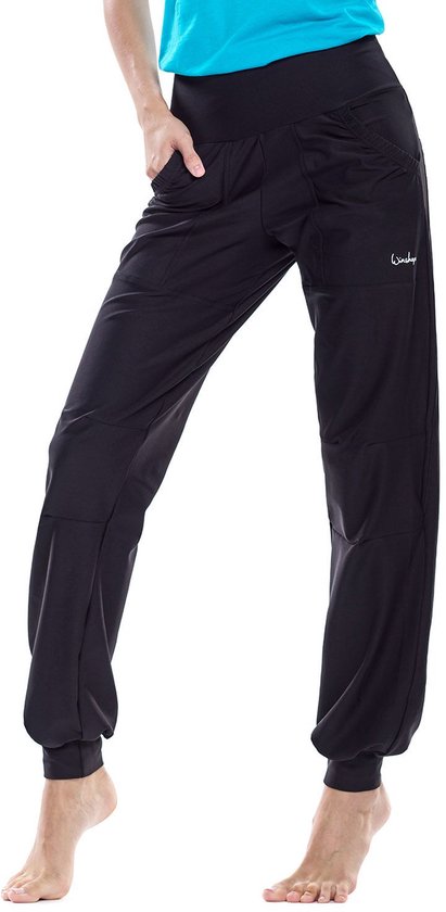 Close-up van een zwarte, nauwsluitende joggingbroek met logo op de heup, gedragen door een model met een turquoise shirt.