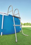 Grijze zwembadladder, zijaanzicht, bevestigd aan een ronde blauwe zwembad.