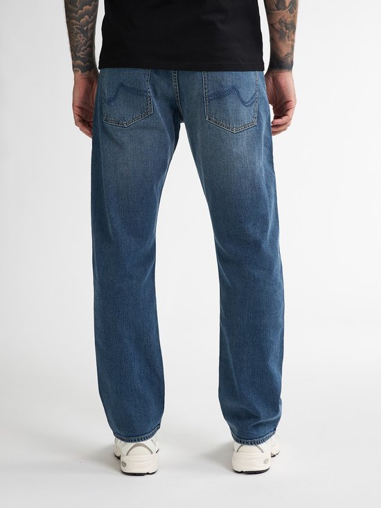 Man met tatoeages, achterkant van blauwe jeans.